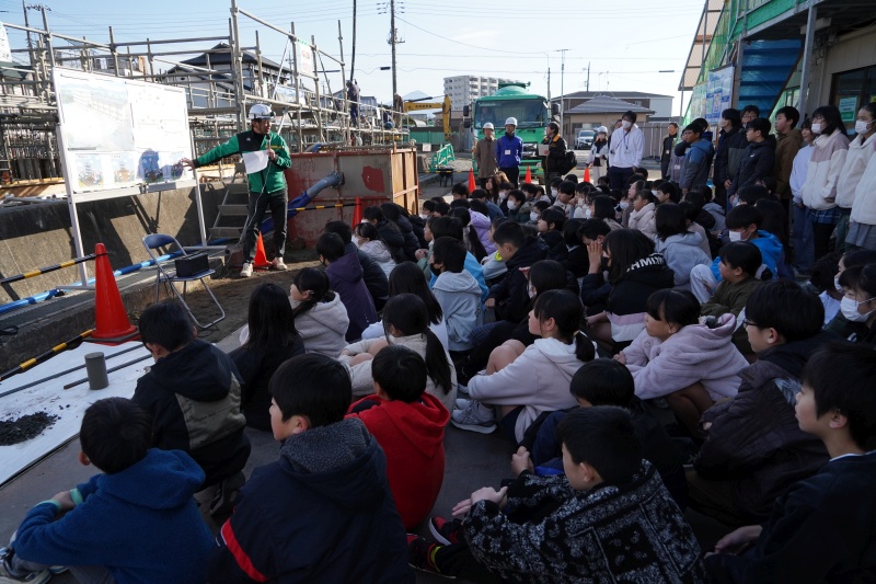 工事現場で説明を聞く児童