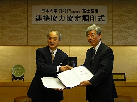 協定書を交換し握手する佐藤学部長と小室市長